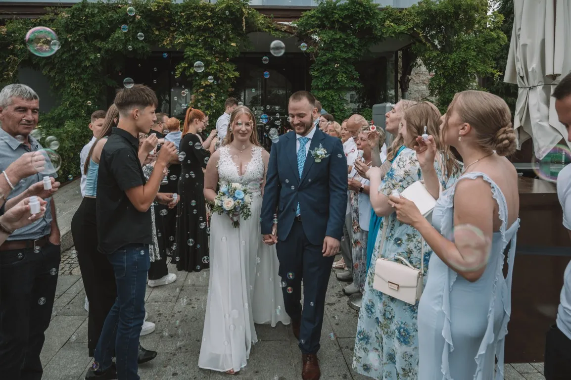 Poročna fotografija mladoporočencev; ujet pristen trenutek z naravno svetlobo in umirjeno kompozicijo v dokumentarnem slogu.